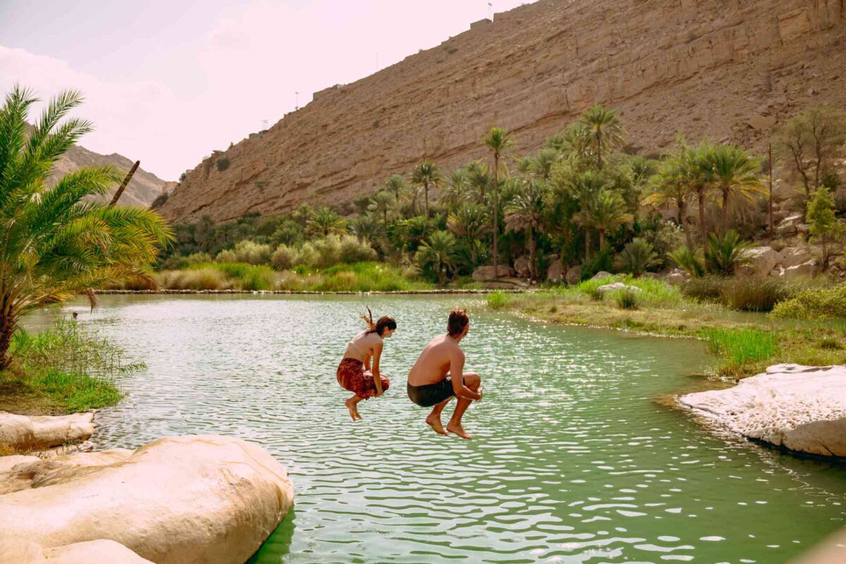 Tourists jumping into the water of an oasis.