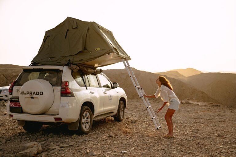 Frau, die ein Dachzelt auf einem 4x4 in Oman aufbaut.